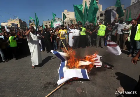 Palestinians burn the Israeli and the U.S. flags during a demonstration against the controversial film 'Innocence of Muslims' in Khan Younis southern Gaza strip, on September 14, 2012. The controversial low budget film r...