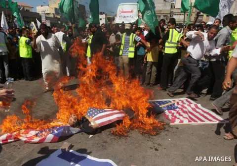 Palestinians burn the Israeli and the U.S. flags during a demonstration against the controversial film 'Innocence of Muslims' in Khan Younis southern Gaza strip, on September 14, 2012. The controversial low budget film r...