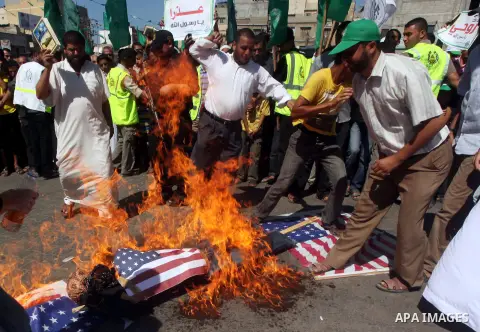 Palestinians burn the Israeli and the U.S. flags during a demonstration against the controversial film 'Innocence of Muslims' in Khan Younis southern Gaza strip, on September 14, 2012. The controversial low budget film r...