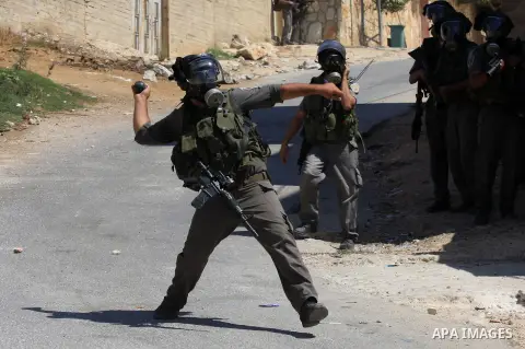 An Israeli border policeman throw a tear gas canister at Palestinian protesters during a demonstration against the expropriation of Palestinian land by Israel in the village of Kafr Qaddum, near the West Bank city of Nab...