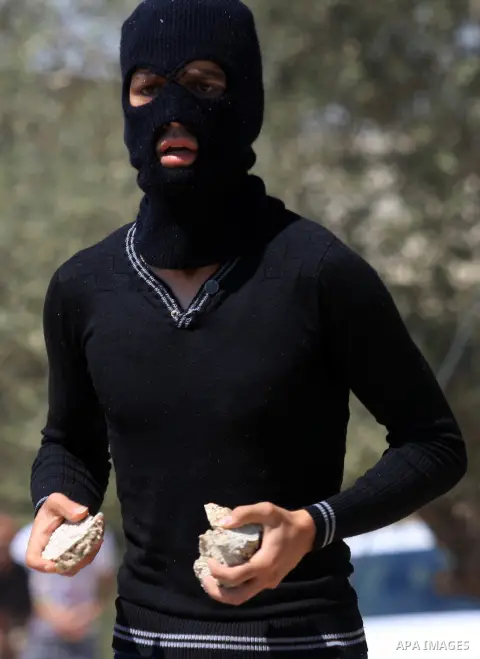 A Palestinian protester throws stones at Israeli troops during a demonstration against the expropriation of Palestinian land by Israel in the village of Kafr Qaddum, near the West Bank city of Nablus, on Sept. 14, 2012....