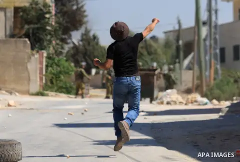 A Palestinian protester throws stones at Israeli troops during a demonstration against the expropriation of Palestinian land by Israel in the village of Kafr Qaddum, near the West Bank city of Nablus, on Sept. 14, 2012....