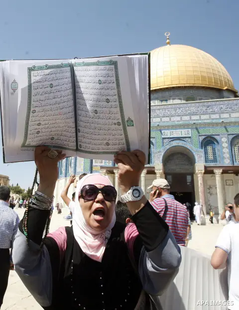 A Palestinian woman holds up a copy of Holy Qur'an during a demonstration against the controversial film 'Innocence of Muslims' in front of al-Aqsa Mosqe in Jerusalem, on September 14, 2012. The controversial low budget...