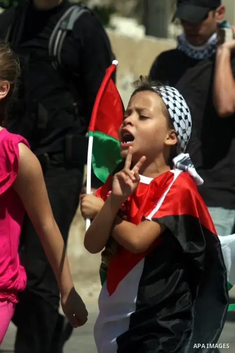 A Palestinian girl holds up national flags during a protest against the confiscation of Palestinian land to expand Jewish settlements in the West Bank village of Nabi Saleh near Ramallah on September 14, 2012.The weekly...
