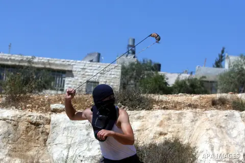A Palestinian youth uses a slingshot to hurl a stone during a protest against the confiscation of Palestinian land to expand Jewish settlements in the West Bank village of Nabi Saleh near Ramallah on September 14, 2012.T...