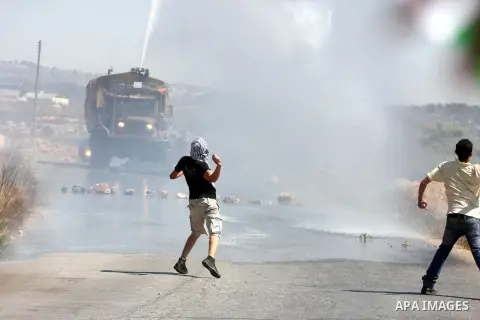 Palestinians throw stones at an Israeli foul smelling water cannon during clashes at a weekly protest against a nearby Jewish settlement, in the West Bank village of Nabi Saleh, near Ramallah, on Friday, Sept 14, 2012. T...