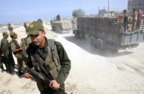 Palestinians ride a lorry carries building materials while Palestinian border police stand along the Gaza-Egypt border in Rafah, in the southern Gaza Strip, on Sept. 15, 2012. The tunnels trade, which analysts estimate i...