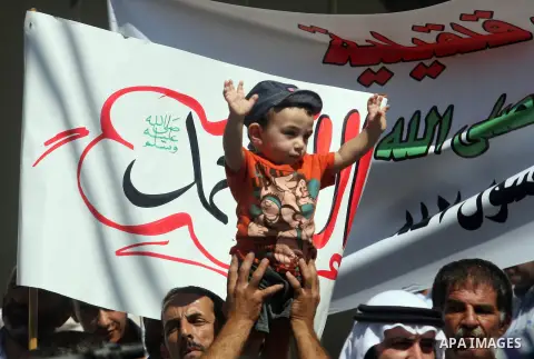 A Palestinian man carries his child during a peaceful sit-in in the West Bank city of Ramallah on September 17, 2012 against an anti-Islam film that has sparked violent demonstrations in the Muslim world. The low-budget,...