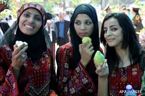 Palestinian girls wear traditional dress and eat guava fruits, during the guava festival in the West Bank city of Qalqilya, Sept. 17, 2012. Photo by Nedal Eshtayah