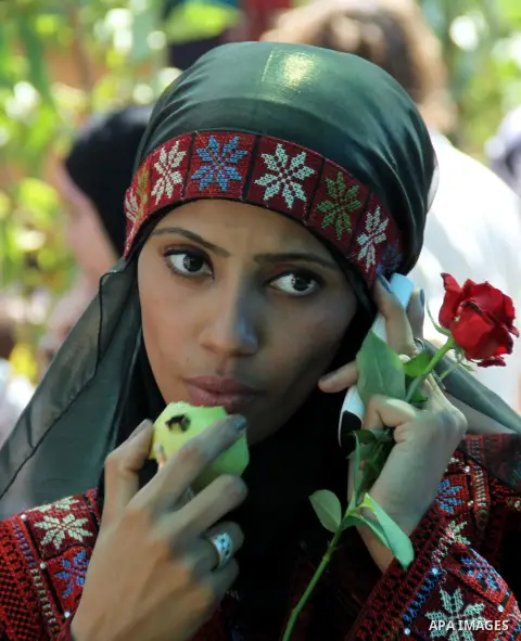 A Palestinian girl wears a traditional dress and eats a guava fruit, during the guava festival in the West Bank city of Qalqilya, Sept. 17, 2012. Photo by Nedal Eshtayah
