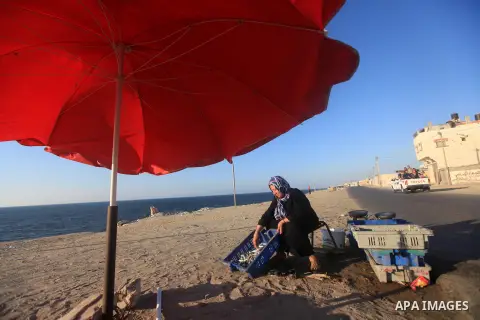 A Palestinian woman displays fish to sale it on the beach of Gaza city, Sept. 18, 2012 . Photo by Majdi Fathi