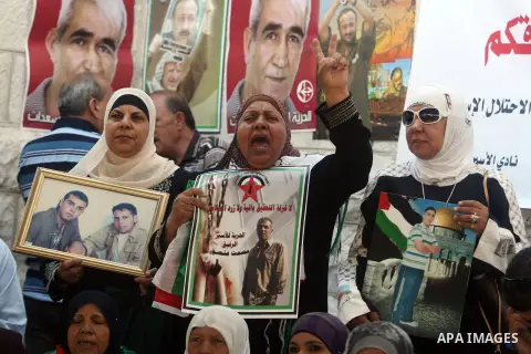 Palestinian women hold pictures of prisoners held in Israeli jails during a sit-in outside the Red Crescent offices near the West Bank city of Ramallah on September 18, 2012 in solidarity with hunger-striking detainees h...