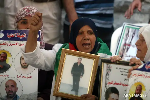 Palestinian women hold pictures of prisoners held in Israeli jails during a sit-in outside the Red Crescent offices near the West Bank city of Ramallah on September 18, 2012 in solidarity with hunger-striking detainees h...