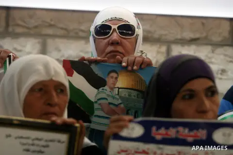 Palestinian women hold pictures of prisoners held in Israeli jails during a sit-in outside the Red Crescent offices near the West Bank city of Ramallah on September 18, 2012 in solidarity with hunger-striking detainees h...