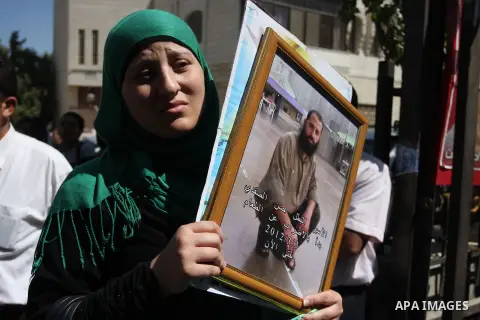 A Palestinian woman holds picture of prisoner held in Israeli jails during a sit-in outside the Red Crescent offices near the West Bank city of Ramallah on September 18, 2012 in solidarity with hunger-striking detainees...