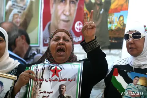 Palestinian women hold pictures of prisoners held in Israeli jails during a sit-in outside the Red Crescent offices near the West Bank city of Ramallah on September 18, 2012 in solidarity with hunger-striking detainees h...
