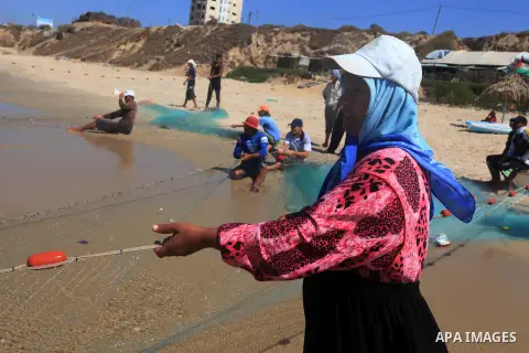 A Palestinian fisherwoman helps her husband to tow his trawl from the sea in Deir al-Balah Palestinian refugee camp, central of Gaza Strip, on September 19, 2012. Photo by Majdi Fathi