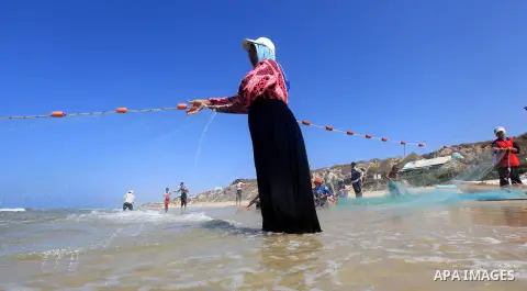 A Palestinian fisherwoman helps her husband to tow his trawl from the sea in Deir al-Balah Palestinian refugee camp, central of Gaza Strip, on September 19, 2012. Photo by Majdi Fathi