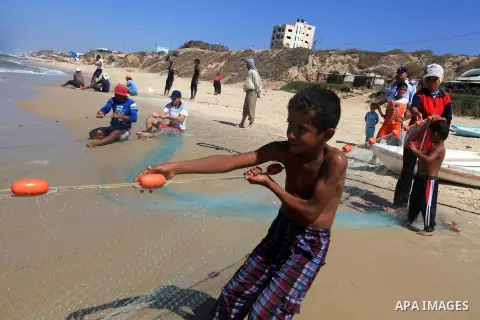 A Palestinian boy helps his father to tow his trawl from the sea in Deir al-Balah Palestinian refugee camp, central of Gaza Strip, on September 19, 2012. Photo by Majdi Fathi