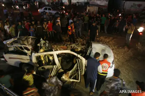 Palestinians gather around the wreckage of a car targeted by an Israeli aircraft in the town of Rafah in southern Gaza Strip on September 19, 2012. An Israeli air strike on the Gaza Strip killed two Palestinians and woun...