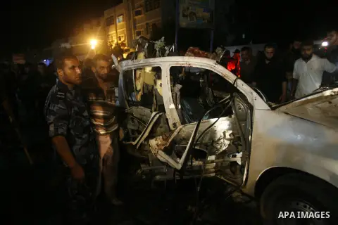 Palestinians gather around the wreckage of a car targeted by an Israeli aircraft in the town of Rafah in southern Gaza Strip on September 19, 2012. An Israeli air strike on the Gaza Strip killed two Palestinians and woun...