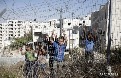 Palestinian refugee children stand behind the barrier during sealing off the Ras Khamis Checkpoint northen jerusalem on Sept. 20, 2012. The Israeli Ministry of Defence has announced its plans to seal off one of two check...