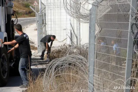 Palestinian refugee children look at Israeli laborers during sealing off the Ras Khamis Checkpoint northen jerusalem on Sept. 20, 2012. The Israeli Ministry of Defence has announced its plans to seal off one of two check...