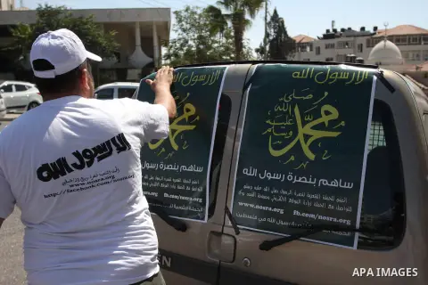 A Palestinians youth pastes a poster on acar reading in Arabic "anyone but prophet Muhammad" during a campaign called by Palestinian activists against the anti-Islam movie entitled 'Innocence of Muslims' made in the U.S....