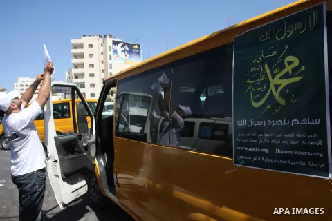 A Palestinians youth pastes a poster on acar reading in Arabic "anyone but prophet Muhammad" during a campaign called by Palestinian activists against the anti-Islam movie entitled 'Innocence of Muslims' made in the U.S....