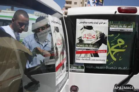 A Palestinians youth pastes a poster on acar reading in Arabic "anyone but prophet Muhammad" during a campaign called by Palestinian activists against the anti-Islam movie entitled 'Innocence of Muslims' made in the U.S....