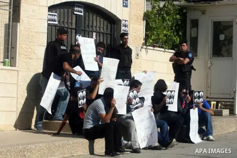 Palestinian activists hold placards as they block the entrance of the EU police office during a protest refusal to the policy of European Union toward Palestinian issue and the prisoners in the Israeli jails, in the West...