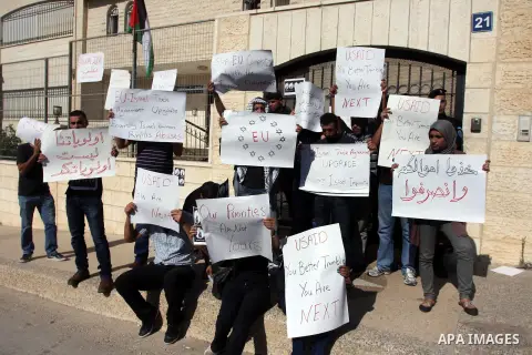 Palestinian activists hold placards as they block the entrance of the EU police office during a protest refusal to the policy of European Union toward Palestinian issue and the prisoners in the Israeli jails, in the West...