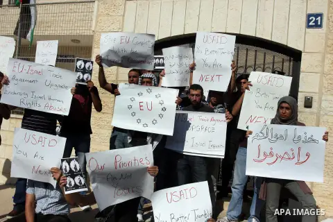 Palestinian activists hold placards as they block the entrance of the EU police office during a protest refusal to the policy of European Union toward Palestinian issue and the prisoners in the Israeli jails, in the West...