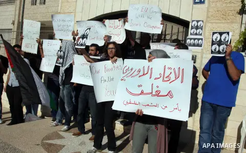 Palestinian activists hold placards as they block the entrance of the EU police office during a protest refusal to the policy of European Union toward Palestinian issue and the prisoners in the Israeli jails, in the West...