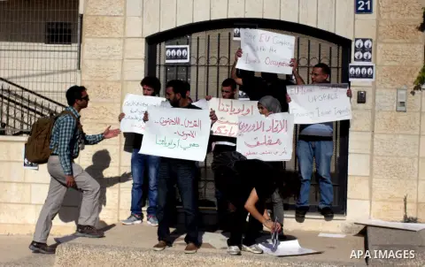 Palestinian activists hold placards as they block the entrance of the EU police office during a protest refusal to the policy of European Union toward Palestinian issue and the prisoners in the Israeli jails, in the West...
