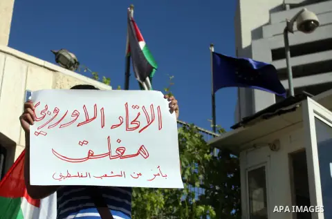 A Palestinian activist holds a placard reading in Arabic "EU Closed, by order of Palestinians" during a protest refusal to the policy of European Union toward Palestinian issue and the prisoners in the Israeli jails, in...