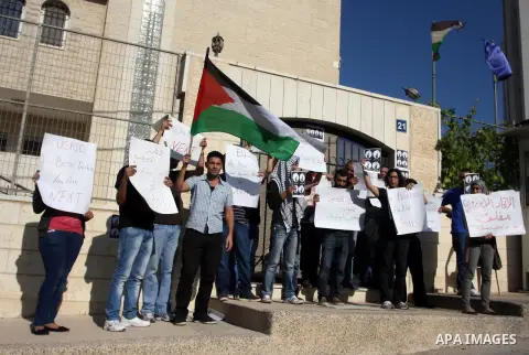 Palestinian activists hold placards as they block the entrance of the EU police office during a protest refusal to the policy of European Union toward Palestinian issue and the prisoners in the Israeli jails, in the West...