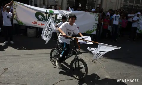 A Palestinian boy rides his bicycle and waves a flags during a protest in the West Bank town of Ramallah against an anti-Islam movie made in the U.S. and French cartoons said to insult the Prophet Muhammad, 21 September...