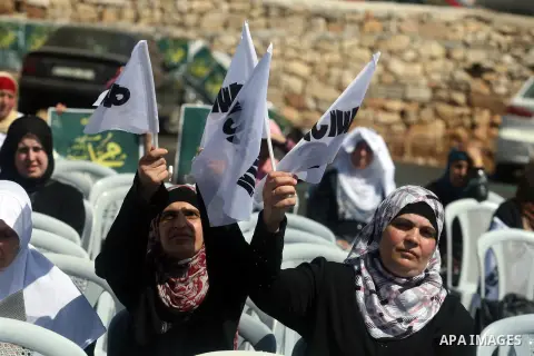 Palestinian women wave flags during a protest in the West Bank town of Ramallah against an anti-Islam movie made in the U.S. and French cartoons said to insult the Prophet Muhammad, 21 September 2012. Photo by Issam Rima...