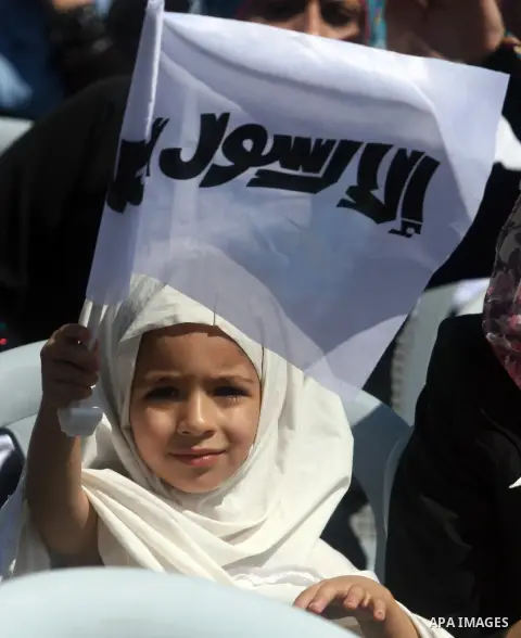 A Palestinian girl holds a banner reading in Arabic "Anyone but prophet Muhammad" and shout slogans during a protest in the West Bank town of Ramallah against an anti-Islam movie made in the U.S. and French cartoons said...