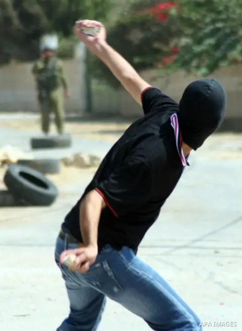 A Palestinian protester throws stones at Israeli soldiers during a demonstration against the expropriation of Palestinian land by Israel in the village of Kfar Qaddum, near the West Bank city of Nablus, on september 21,...