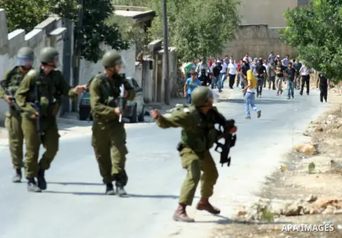 An Israeli soldier throws tear gas canister toward Palestinian protesters during a demonstration against the expropriation of Palestinian land by Israel in the village of Kfar Qaddum, near the West Bank city of Nablus, o...