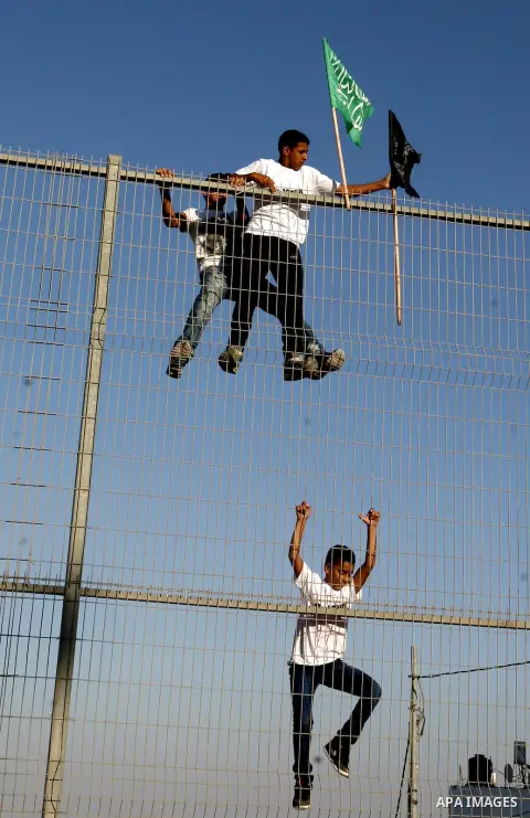 Palestinian boys they place banners on a fence denouncing an US-produced amateur film mocking Islam's Prophet Mohammed and cartoons published in a French satirical magazine Charlie Hebdo in the Issawiya district of Arab...