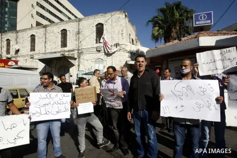 Palestinian protesters hold placareds during a protest against the Paris Protocol and the high cost of living in the West Bank city of Nablus on September 24, 2012. Photo by Nedal Eshtayah