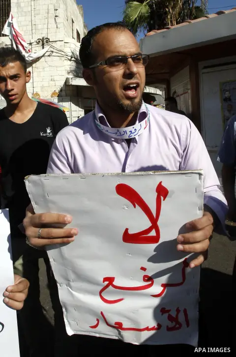 A Palestinian protester holds a placard reading "No for rising the cost of living" during a protest against the Paris Protocol in the West Bank city of Nablus on September 24, 2012. Photo by Nedal Eshtayah