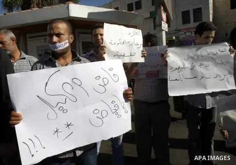 Palestinian protesters hold placareds during a protest against the Paris Protocol and the high cost of living in the West Bank city of Nablus on September 24, 2012. Photo by Nedal Eshtayah