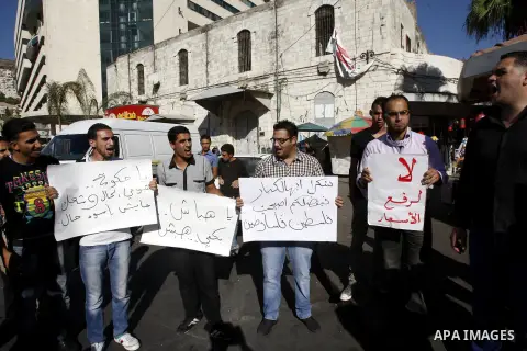 Palestinian protesters hold placareds during a protest against the Paris Protocol and the high cost of living in the West Bank city of Nablus on September 24, 2012. Photo by Nedal Eshtayah