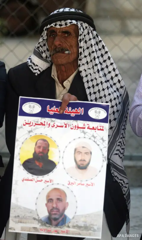 A Palestinian man holds picture of a prisoner held in Israeli jails during a sit-in outside the Red Crescent offices near the West Bank city of Ramallah on September 25, 2012 in solidarity with hunger-striking detainees...