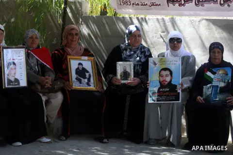 Palestinian women hold pictures of prisoners held in Israeli jails during a sit-in outside the Red Crescent offices near the West Bank city of Ramallah on September 25, 2012 in solidarity with hunger-striking detainees h...