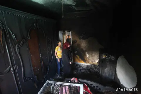 Palestinians inspect the damage in the bedroom of one-year-old Fathi Baghdadi, who died after a fire from a candle that swept through their home in the Bureij refugee camp in the center of the Gaza Strip on September 26,...